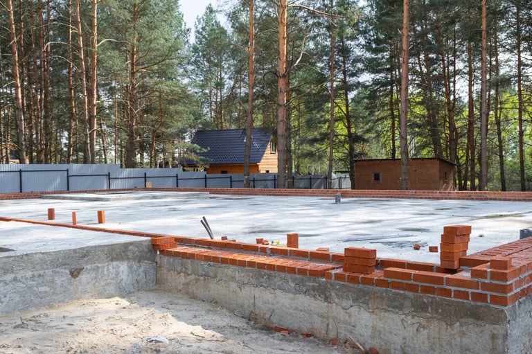Concrete foundation construction site with pipes and building materials