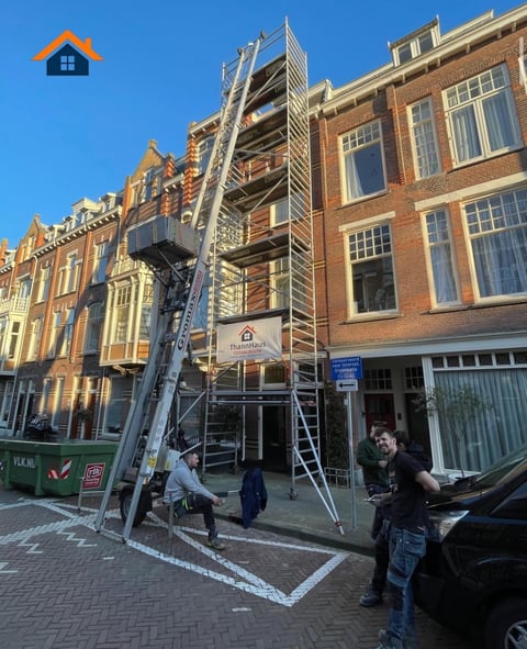 Construction scaffolding on a brick building facade between historic Dutch architecture buildings on a sunny day